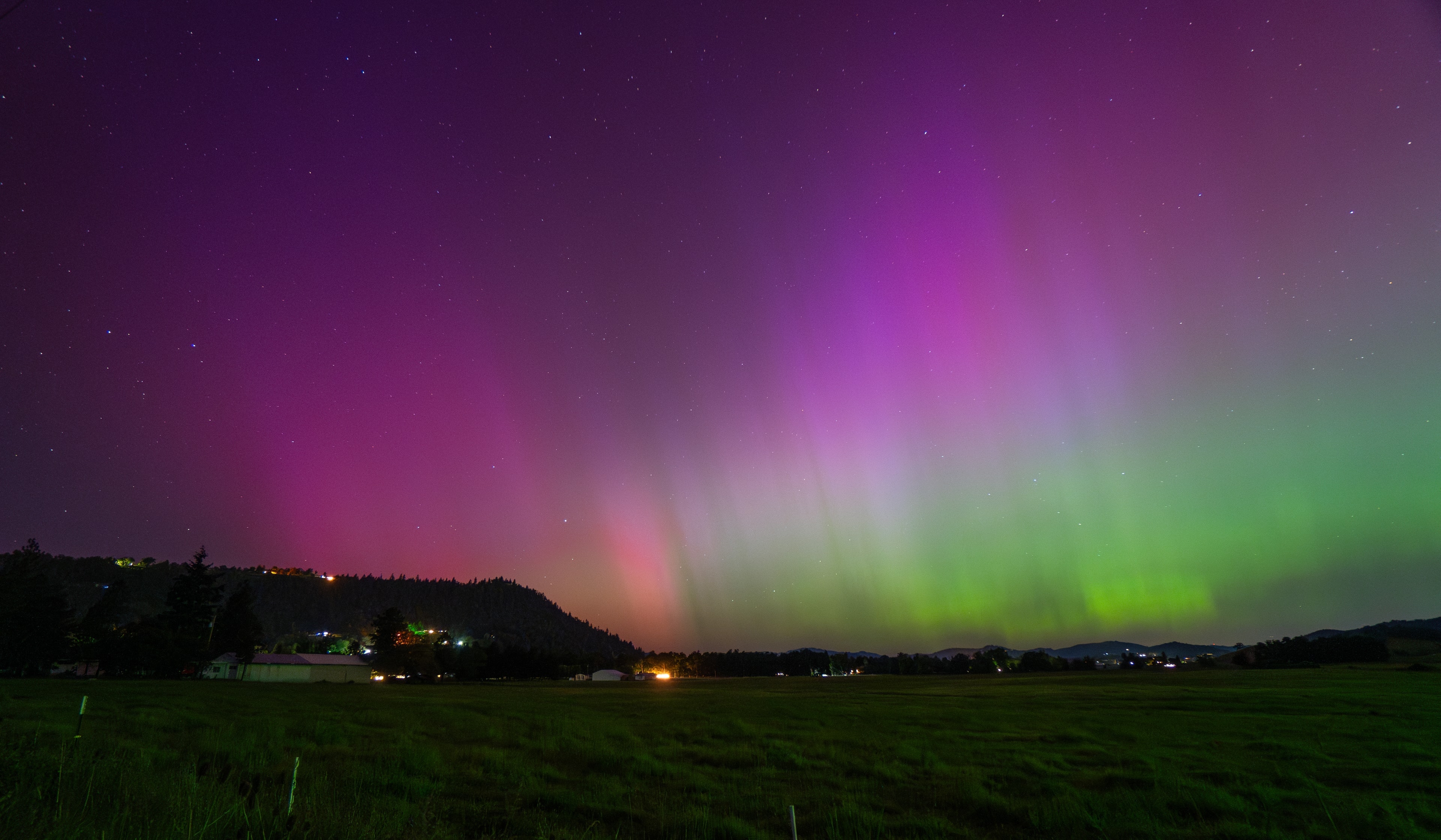 Northern lights in pink and green over dark fields outside Roseburg on a May night