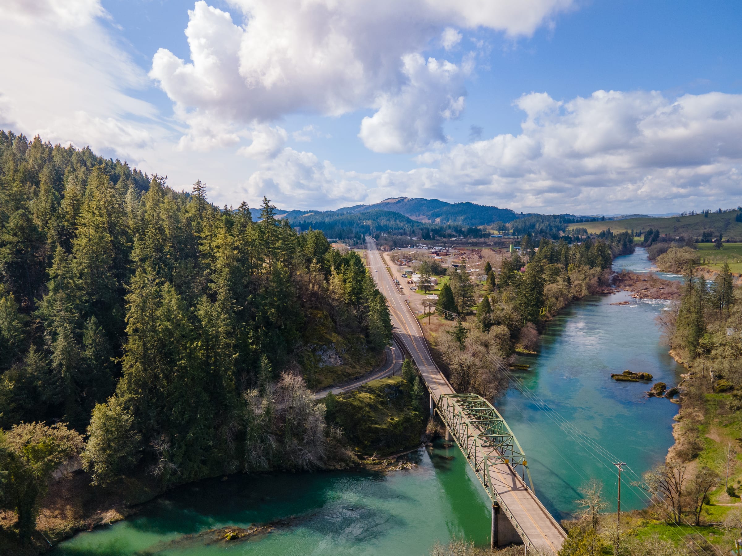 A green steel bridge over the North Umpqua River at Glide in March, seen from the air with the town beyond