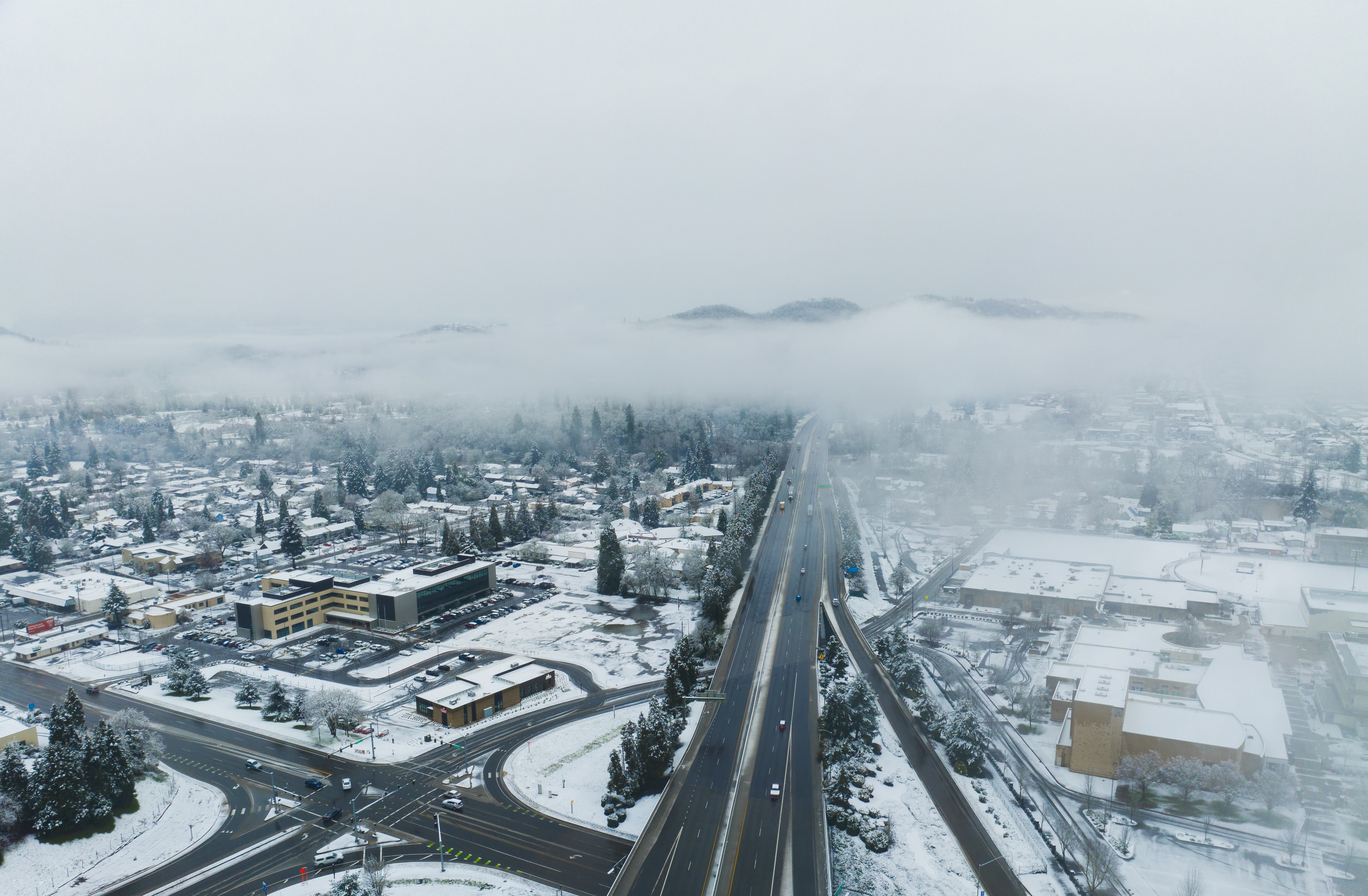 Interstate 5 through Roseburg after a March snowfall, seen from Mount Nebo with fog over the town