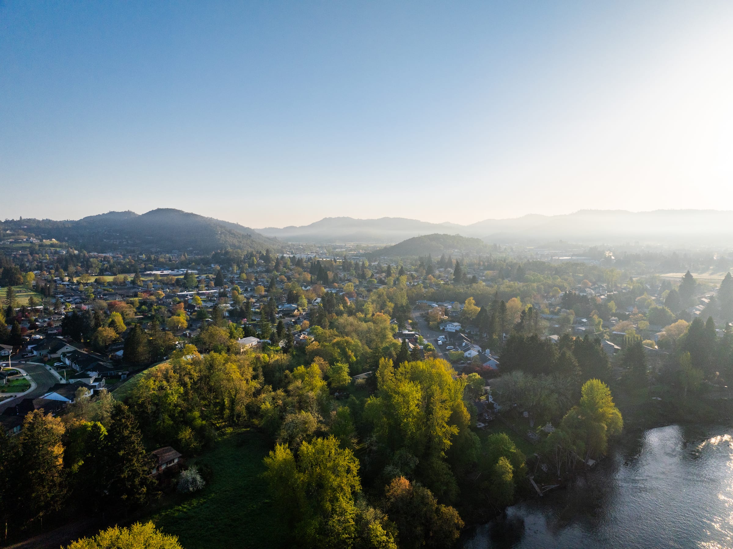 Roseburg from the air on a hazy April morning, green trees, houses and the South Umpqua River below the hills