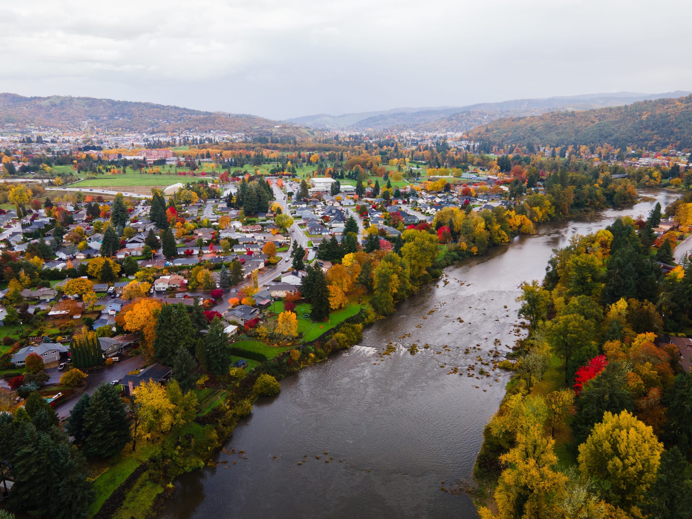 Roseburg from the air in November, autumn trees among the houses and the South Umpqua River running through the town