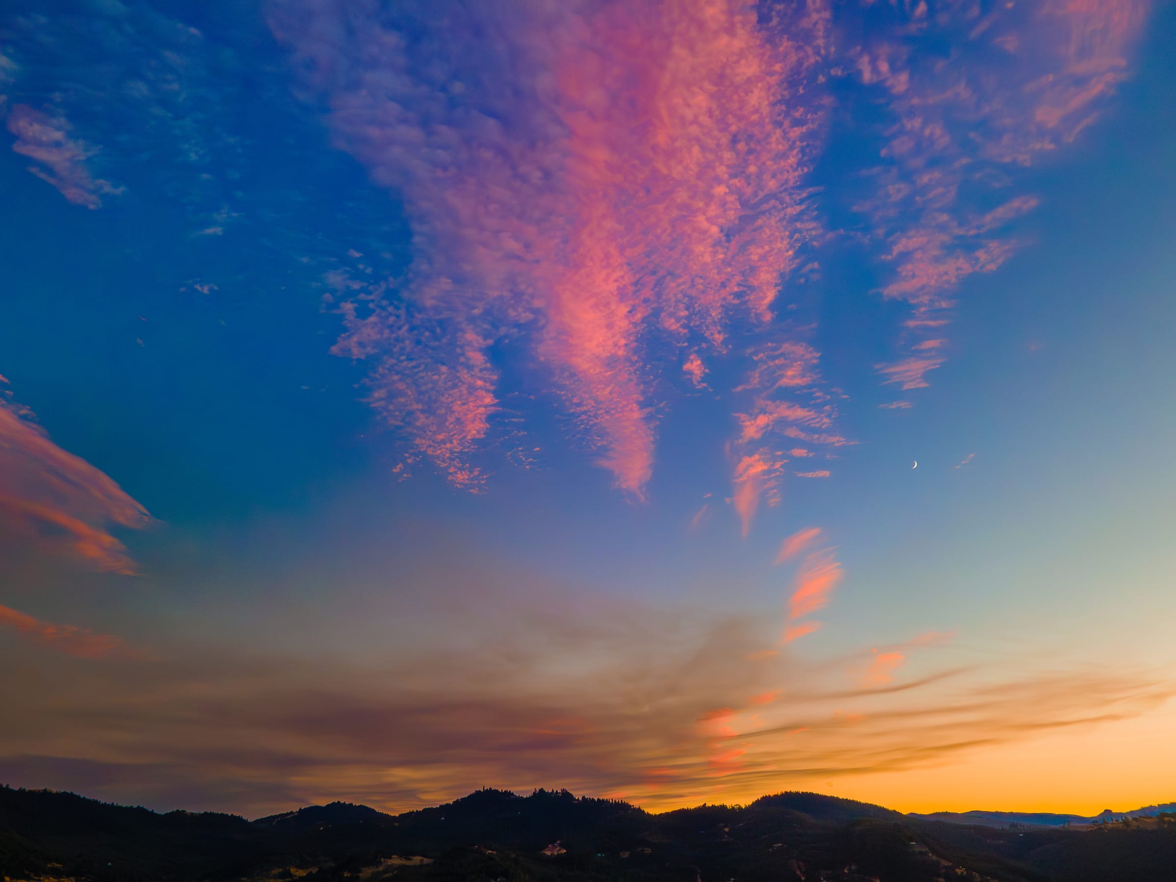 Pink and orange clouds over the dark hills at Roseburg at sunset in July