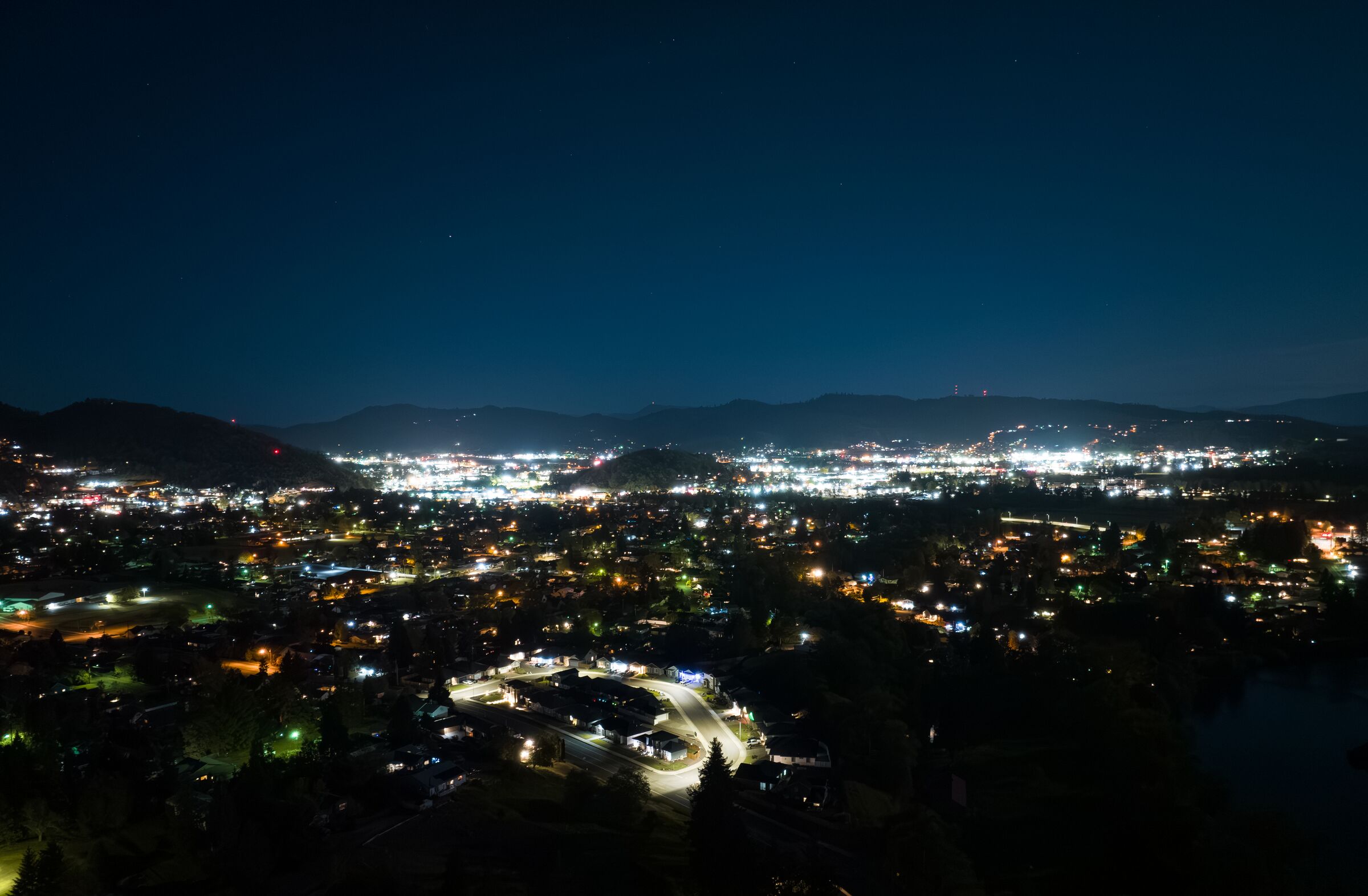 The lights of Roseburg at night in April, spread across the dark valley under the hills