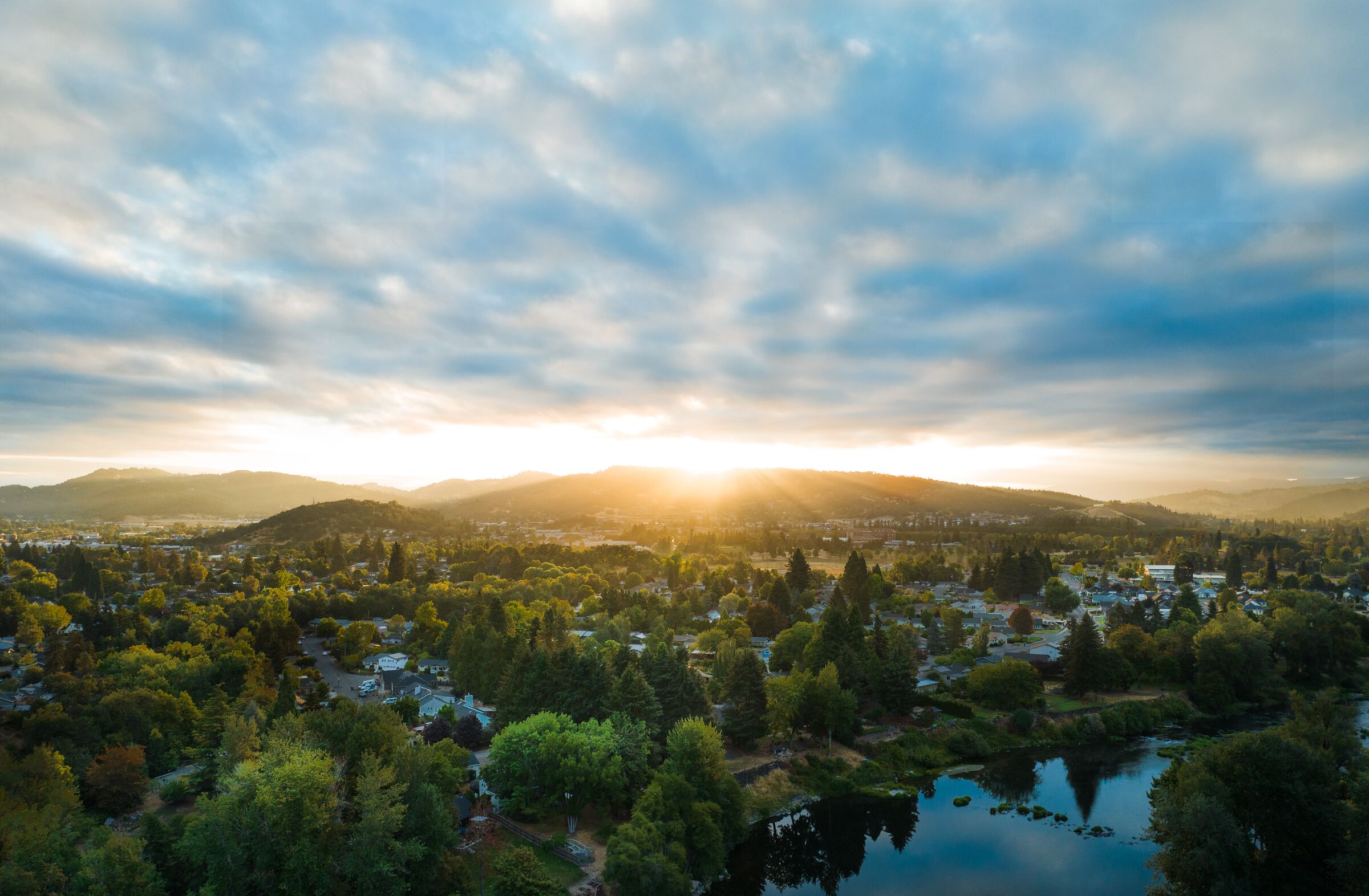 The August sun rising over the hills behind Roseburg, the South Umpqua River among green trees below