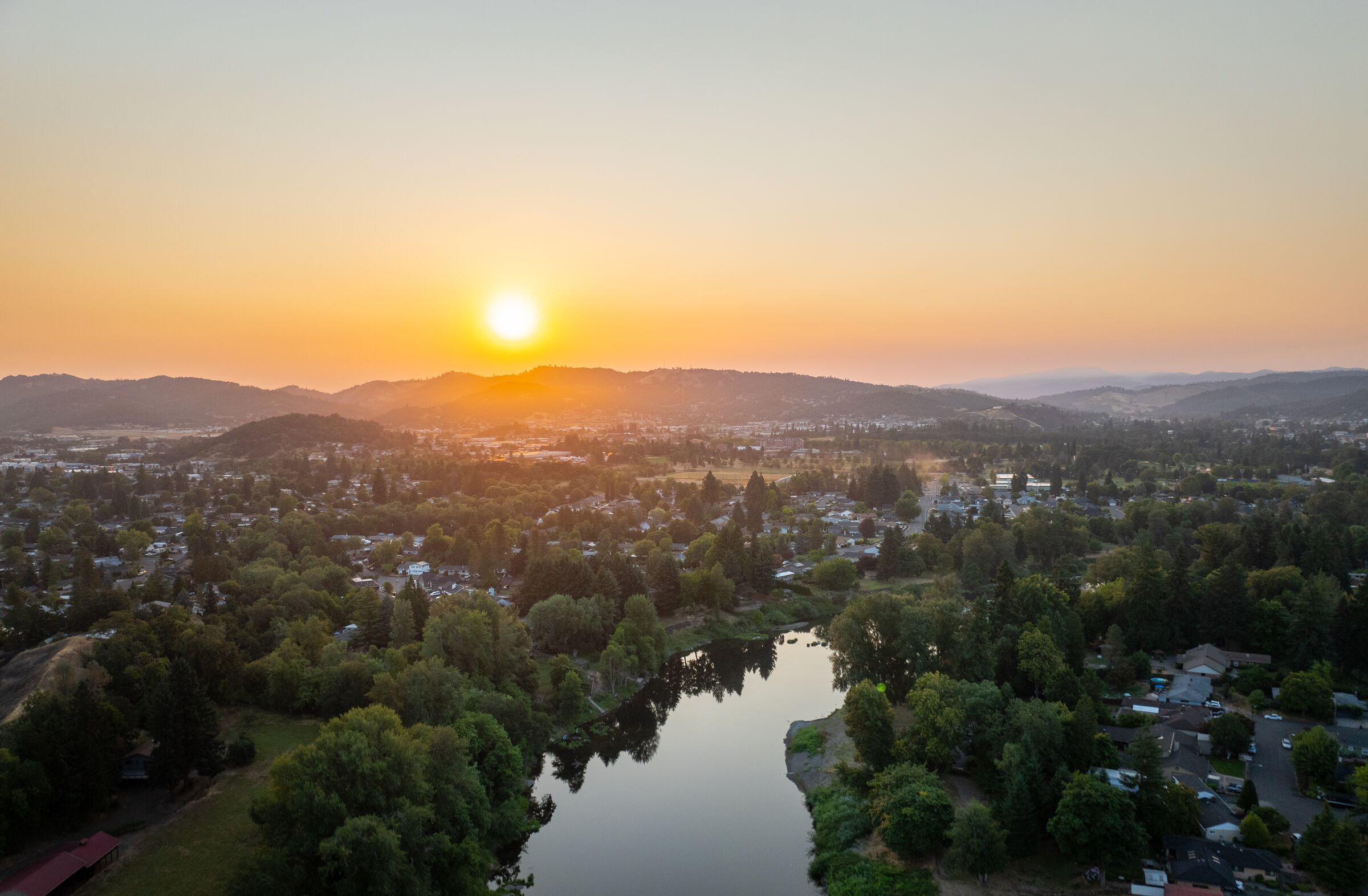 The July sun rising over the hills behind Roseburg, the South Umpqua River still among the trees