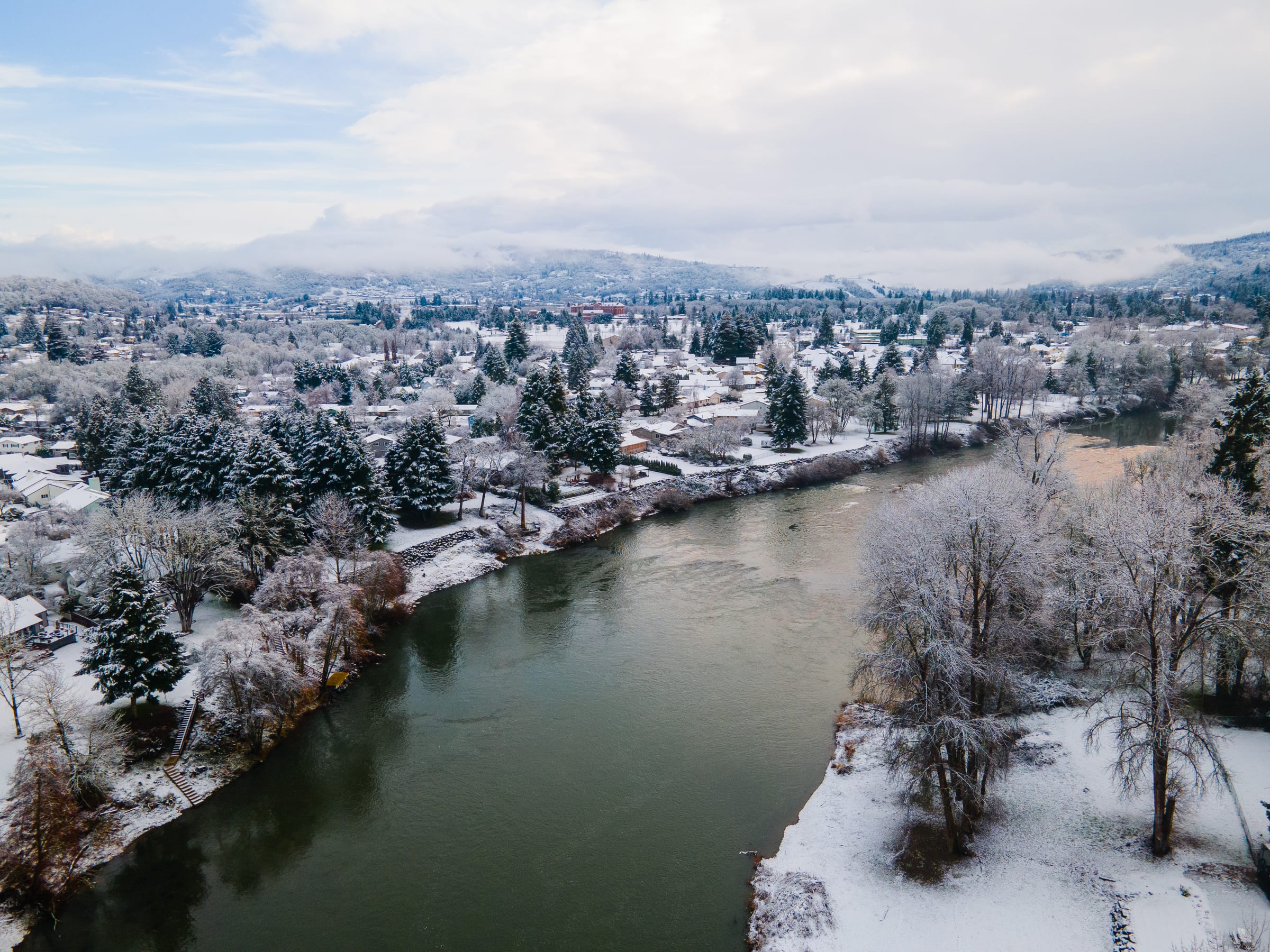 The South Umpqua River through Roseburg after a February snowfall, white trees and rooftops along the banks