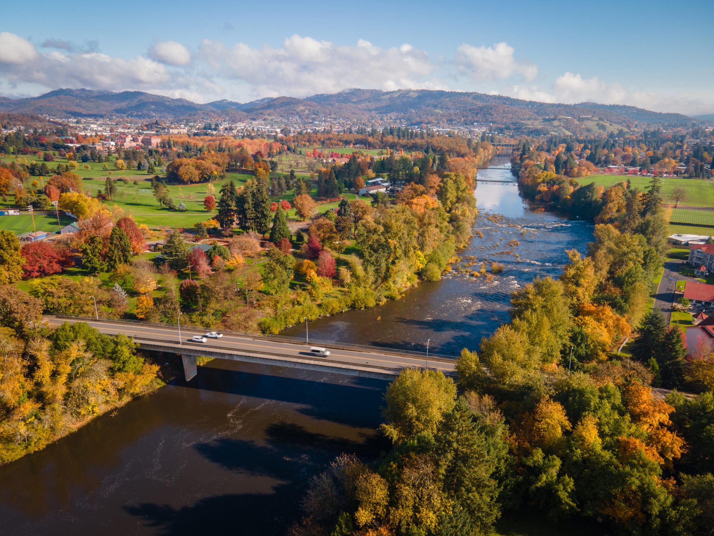 Stewart Park from the air in November, autumn trees along the South Umpqua River and a bridge over it