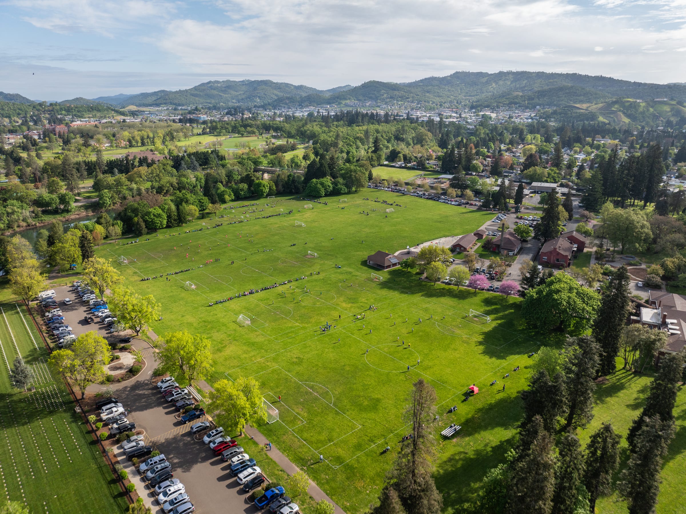 Green playing fields at Stewart Park from the air in April, cars parked along the edge and hills beyond